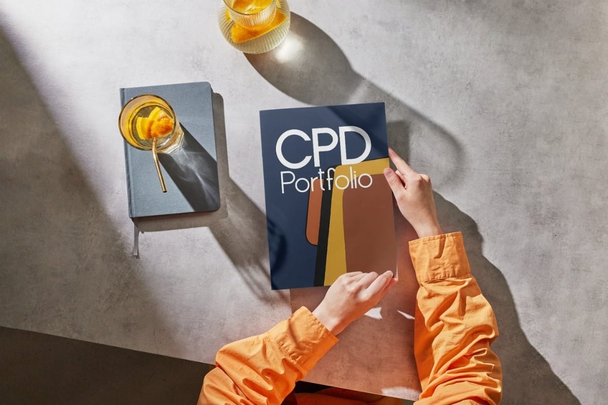 Hands holding a CPD portfolio with drinks nearby.